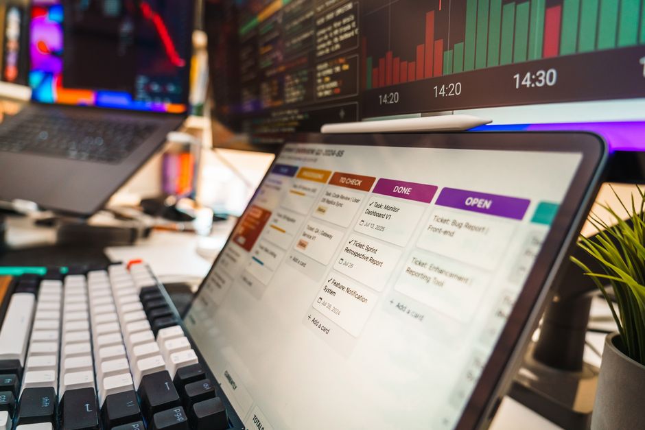 A dynamic office setup featuring multi-screen displays with data charts and project management tools, perfect for tech or business environments.